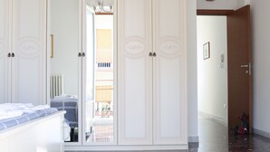 Une chambre dotée d’une grande armoire, d’un lit avec une tête de lit blanche et d’un sol en marbre.
