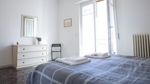 Une chambre à coucher avec un lit, une commode et une fenêtre avec des rideaux.