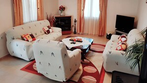 A living room with a sofa, armchairs, a coffee table, a TV, and a decorative plant. - Aloni Home,family holiday,relaxing and quiet place,private parking,garden (moires)