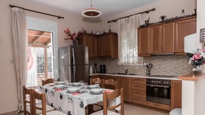 A kitchen with wooden cabinets, a stainless steel refrigerator, a stove, and a dining table set for four. - Aloni Home,family holiday,relaxing and quiet place,private parking,garden (moires)