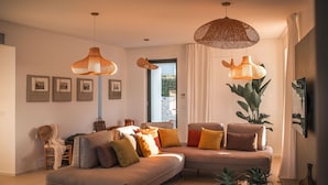 Ein modernes Wohnzimmer mit einer Couch, zwei hängenden Korbstühlen und einer großen Pflanze.