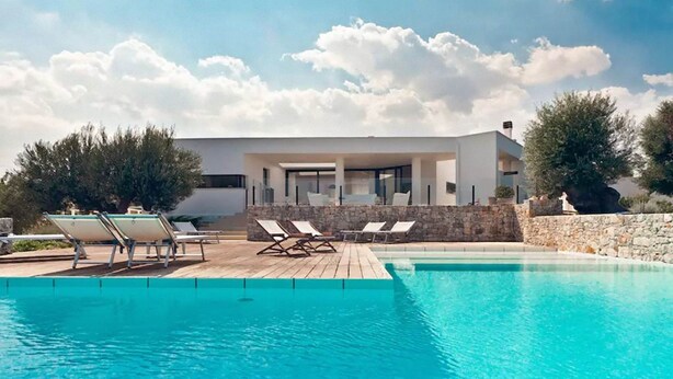 Ein moderner Poolbereich mit Liegestühlen und einer Steinmauer.