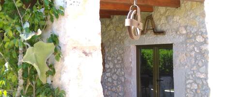 Un edificio de piedra con techo de vigas de madera, una campana colgante y un puerta de cristal.