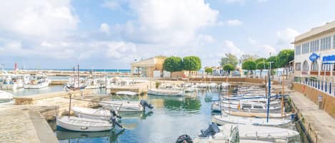 A marina with boats docked, a building with a sign, and a clear sky.