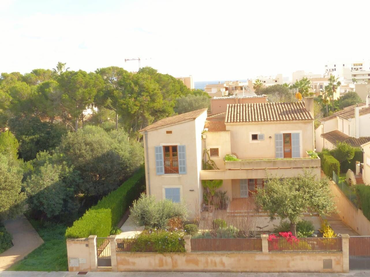 A two-story house with a tiled roof, surrounded by lush greenery and a well-maintained garden.