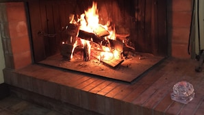 A fireplace with a log fire burning inside a brick fireplace.