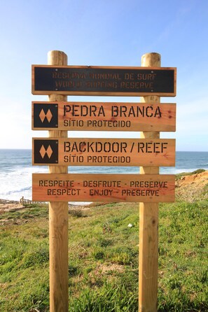 A wooden signpost with multiple directional signs against a coastal backdrop.