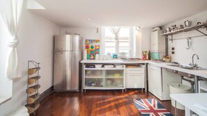 A compact kitchen with a stainless steel refrigerator, white cabinets, and a window providing natural light. - Naples Mergellina with charm  (Napoli)