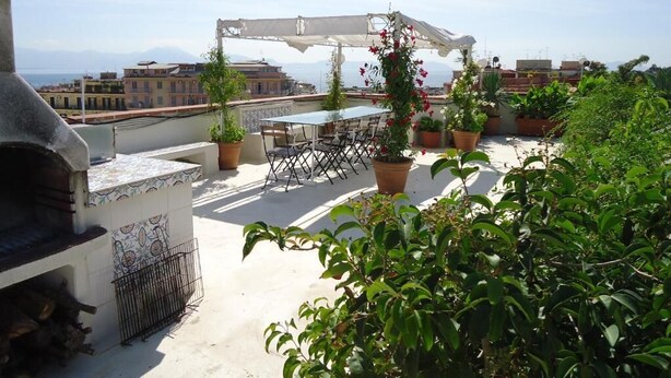 A rooftop terrace with a table and chairs, potted plants, and a pergola. - Naples Mergellina with charm  (Napoli)