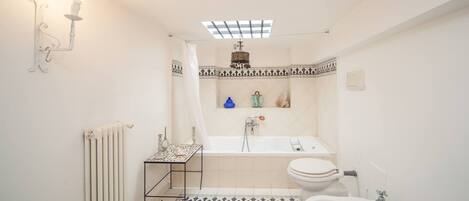 Un baño con piso a cuadros, una bañera, un inodoro y un lavamanos.