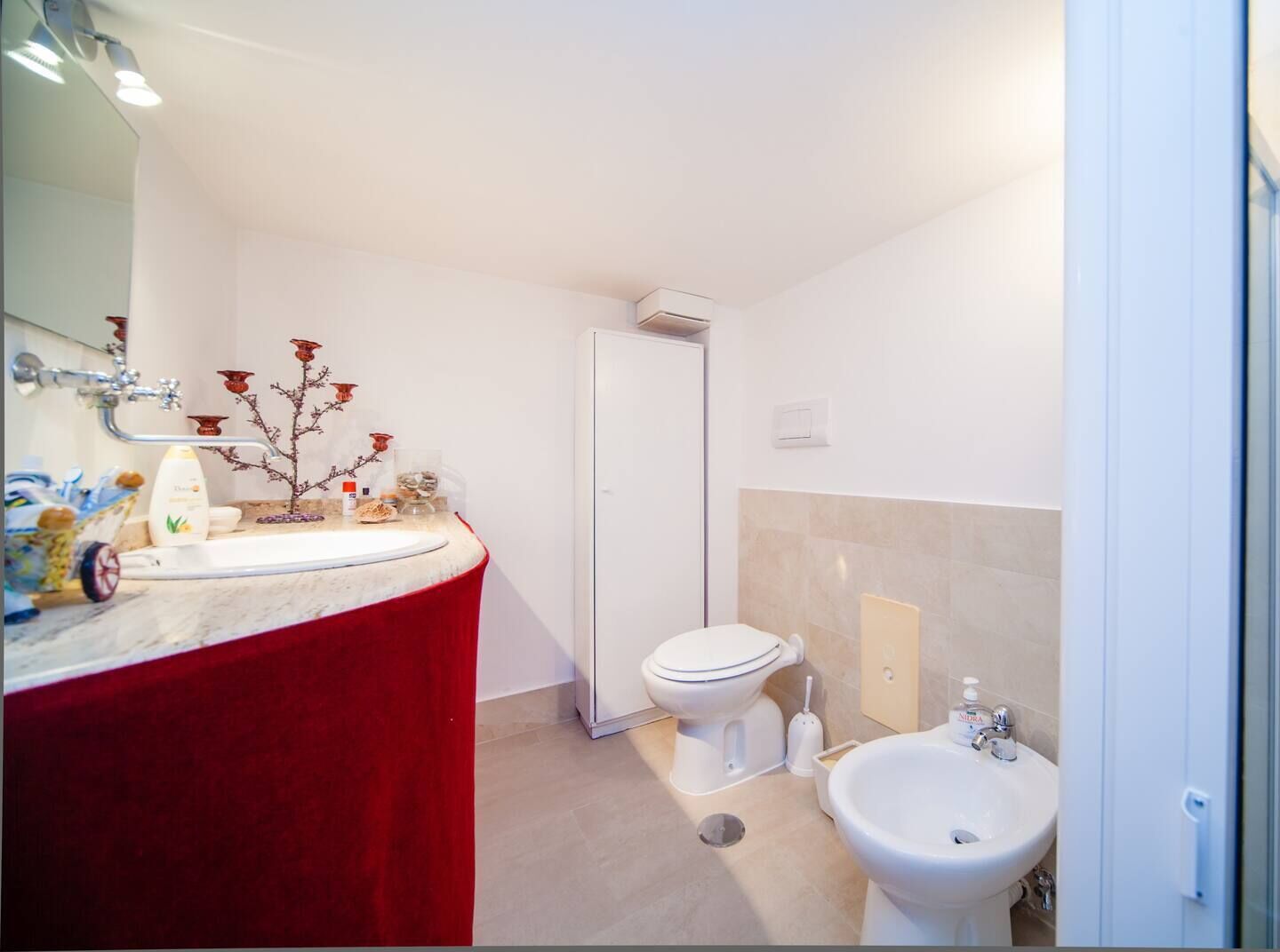 Een badkamer met een wit toilet, een bidet, een wastafel en een spiegel.
