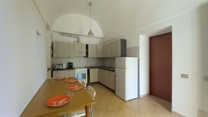 A compact kitchen with a dining table, a refrigerator, a stove, and a microwave. - Authentic Stone Villa with Hot Tub | Valle d'Itria View | Near Alberobello & Sea (Locorotondo)