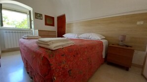 A bedroom with a bed, a nightstand, a window, and a radiator. - Authentic Stone Villa with Hot Tub | Valle d'Itria View | Near Alberobello & Sea (Locorotondo)