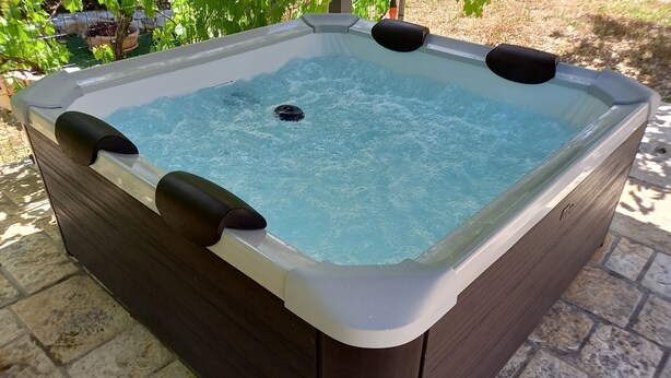 A hot tub with a wooden exterior and a clear water surface. - Authentic Stone Villa with Hot Tub | Valle d'Itria View | Near Alberobello & Sea (Locorotondo)