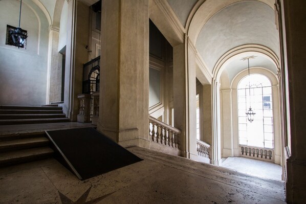 A grand staircase with a black mat at the bottom, leading to a landing with a balustrade. - ALTIERI LOFT PANTHEON (Roma)