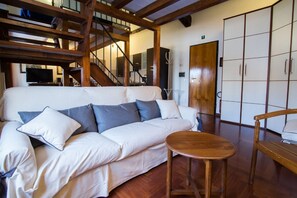 A white sofa with blue cushions, a wooden table, and a wardrobe with sliding doors.