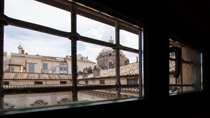 A view through a window with a grid pattern, displaying buildings with traditional architecture and a dome structure in the background. - ALTIERI LOFT PANTHEON (Roma)