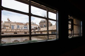 Une vue à travers une fenêtre à carreaux, qui révèle des bâtiments à l’architecture traditionnelle et, au loin, une structure en forme de dôme.