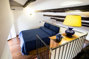 A bedroom with a bed, a wooden nightstand, a lamp, and a rustic ceiling. - ALTIERI LOFT PANTHEON (Roma)