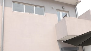 Un edificio moderno con fachada plana, ventanas amplias y un balcón.