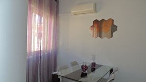 Un comedor moderno con una mesa de vidrio, sillas blancas y un elemento decorativo en la pared.