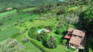Une villa avec piscine, entourée de jardins magnifiquement entretenus et offrant une vue sur des collines verdoyantes.