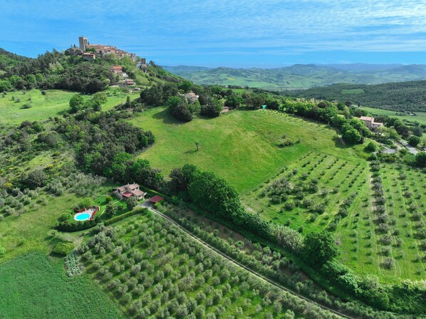 A rural landscape with a castle, rolling hills, and scattered houses.