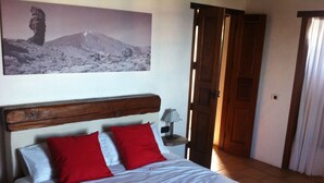 Ein Schlafzimmer mit einem Bett, einem Nachttisch, einer Lampe und einer Tür zu einem anderen Raum.