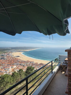 A balcony with a view of a beach and a coastal town.