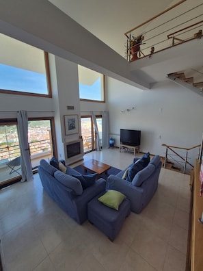 Un soggiorno spazioso con un divano componibile, una TV a schermo piatto e un balcone con vista sulla città.