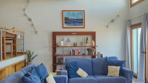 Ein Wohnzimmer mit zwei blauen Sofas, einem Holztisch, einem Bücherregal und einem Gemälde an der Wand.