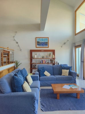 Un soggiorno con due divani blu, un tavolino in legno, una libreria e un quadro appeso al muro.