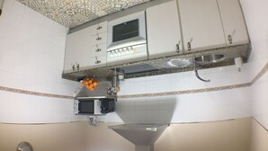 Una cocina con armarios blancos, microondas y lavamanos.