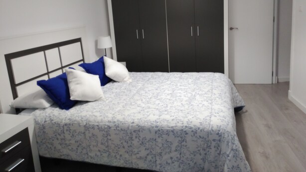 Un dormitorio con cama, armario y mesita de noche.