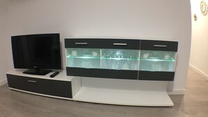 A modern entertainment unit with a flat-screen TV, drawers, and a glass display shelf.