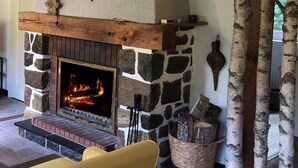Una chimenea de piedra con fuego, un repisa de madera y un muro de piedra.