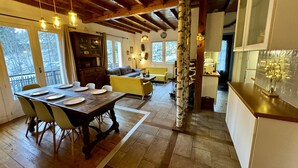 Un comedor amplio con una mesa de madera dispuesta para cuatro personas, un sofá y una cocina de diseño moderno.