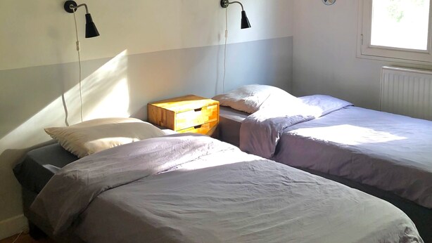 Een slaapkamer met twee bedden, een houten hoofdbord, wandlampen en lijstwerken met dierenafbeeldingen.