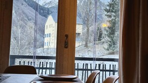 Comedor con una mesa dispuesta para dos personas, con vistas a un paisaje montañoso a través de amplios ventanales.