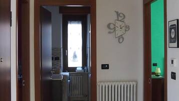A hallway with a radiator, a clock, and a green screen door.