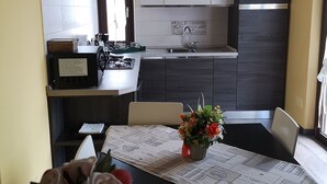 Una cucina moderna con mobili bianchi e in legno scuro, un lavello in acciaio inox e una lampada a sospensione bianca.