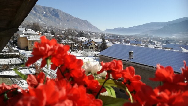 Paesaggio montano con case innevate e un tetto con pannelli solari.