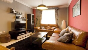 A living room with a leather sofa, a television, and a coffee table. - Beautiful house in Granada just 10min from the center + (PARKING IN THE CENTER) + WIFI (Ambroz)