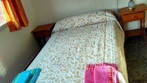 A neatly made bed with a patterned bedspread, two bedside tables, a lamp, and a window with curtains. - Taibilla floor (Los Nietos) (Los Nietos)