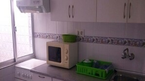 A compact kitchen with white cabinets, a microwave, a small oven, and a sink. - Taibilla floor (Los Nietos) (Los Nietos)