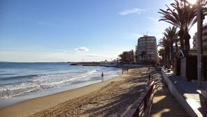A beach with a wooden walkway, palm trees, and buildings in the background. - Registered Holiday home in sunny Rojales on the Costa Blanca (Ciudad Quesada)
