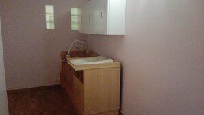 Ein kleines, einbeckeniges Holzwaschbecken mit Wasserhahn, ein Spiegel darüber und ein Schrank über dem Waschbecken.