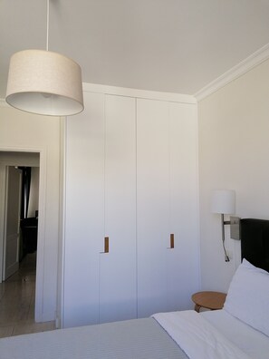 Une chambre à coucher avec un lit, une table de chevet, une lampe et une armoire.