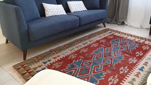 A blue sofa with patterned cushions, a red and beige rug, and a floor lamp.
