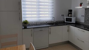 A modern kitchen with a window, white cabinets, a microwave, and a coffee maker.